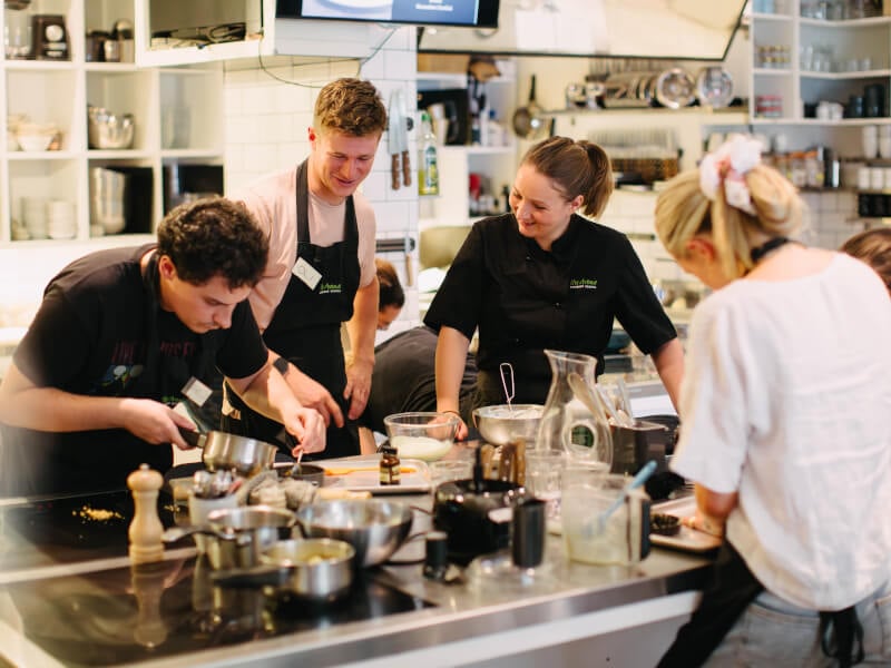 Four people grouped around a bench in an industrial kitchen